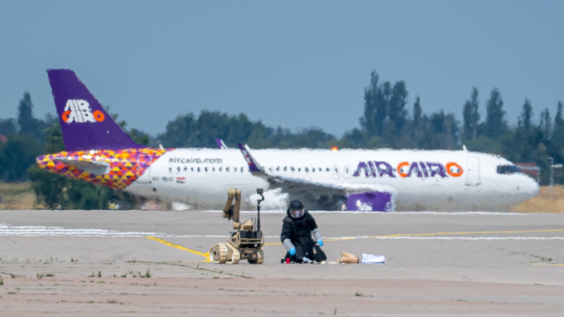 Leipziger Flughafen Schkeuditz - Sprengstoff an Drohne wird von einem Experten mithilfe eines Roboters entschärft. Im Hintergrund steht ein Flugzeug. Leipziger Flughafen Schkeuditz - Sprengstoff an Drohne wird von einem Experten mithilfe eines Roboters entschärft. Im Hintergrund steht ein Flugzeug.