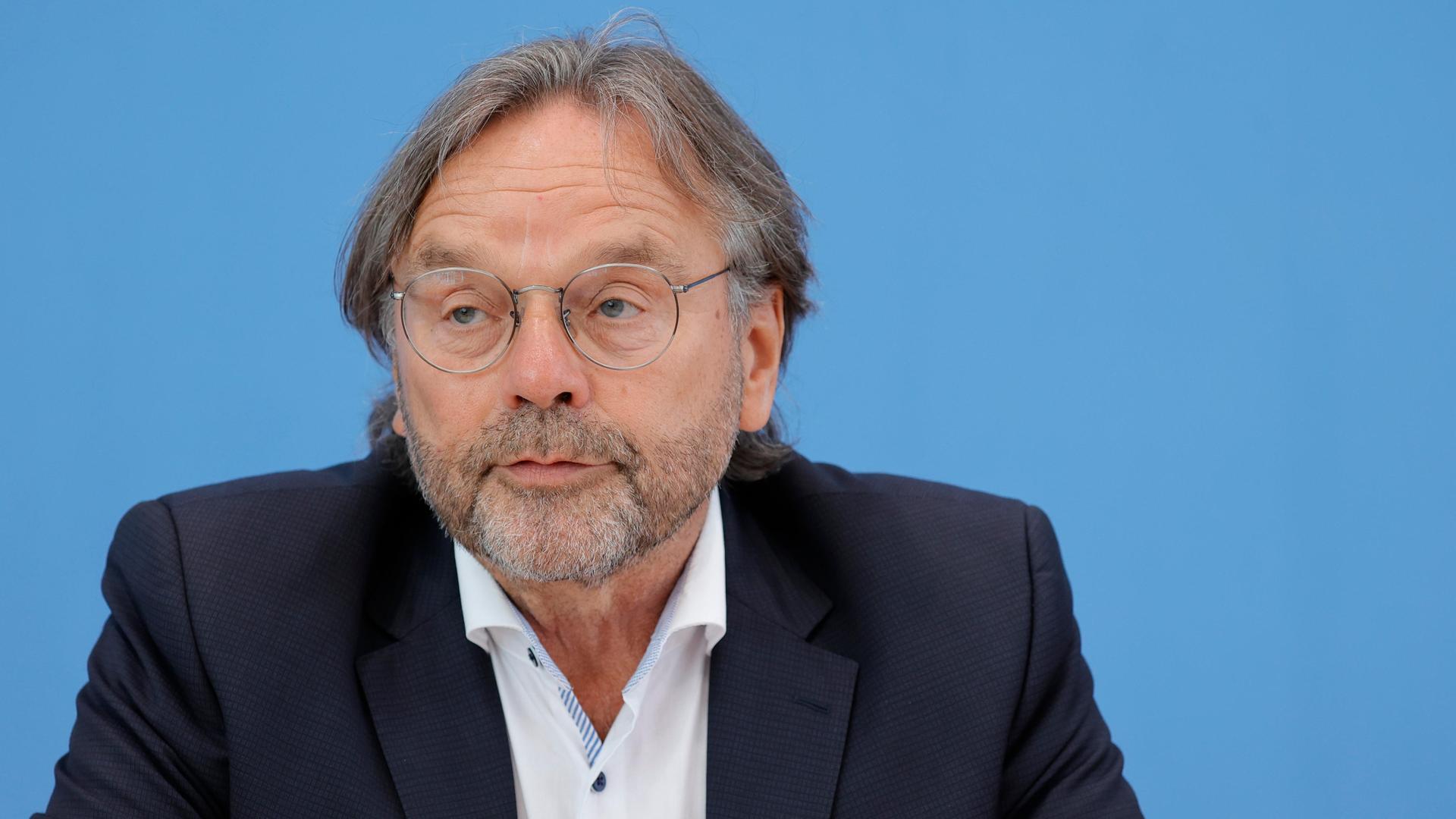 Michael Groß, Präsident der Arbeiterwohlfahrt, sutzt während einer Pressekonferenz an einem Tisch. Im Hintergrund ist eine blaue Wand zu sehen.