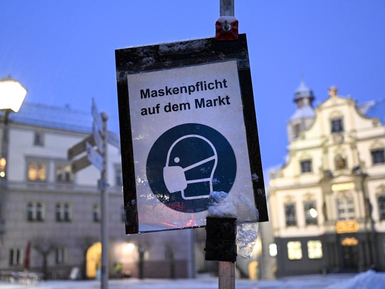 Ein Schild im Januar 2022 wies aufgrund der Corona-Pandemie auf die Maskenpflicht auf dem Marktplatz von Wangen im Allgäu hin.