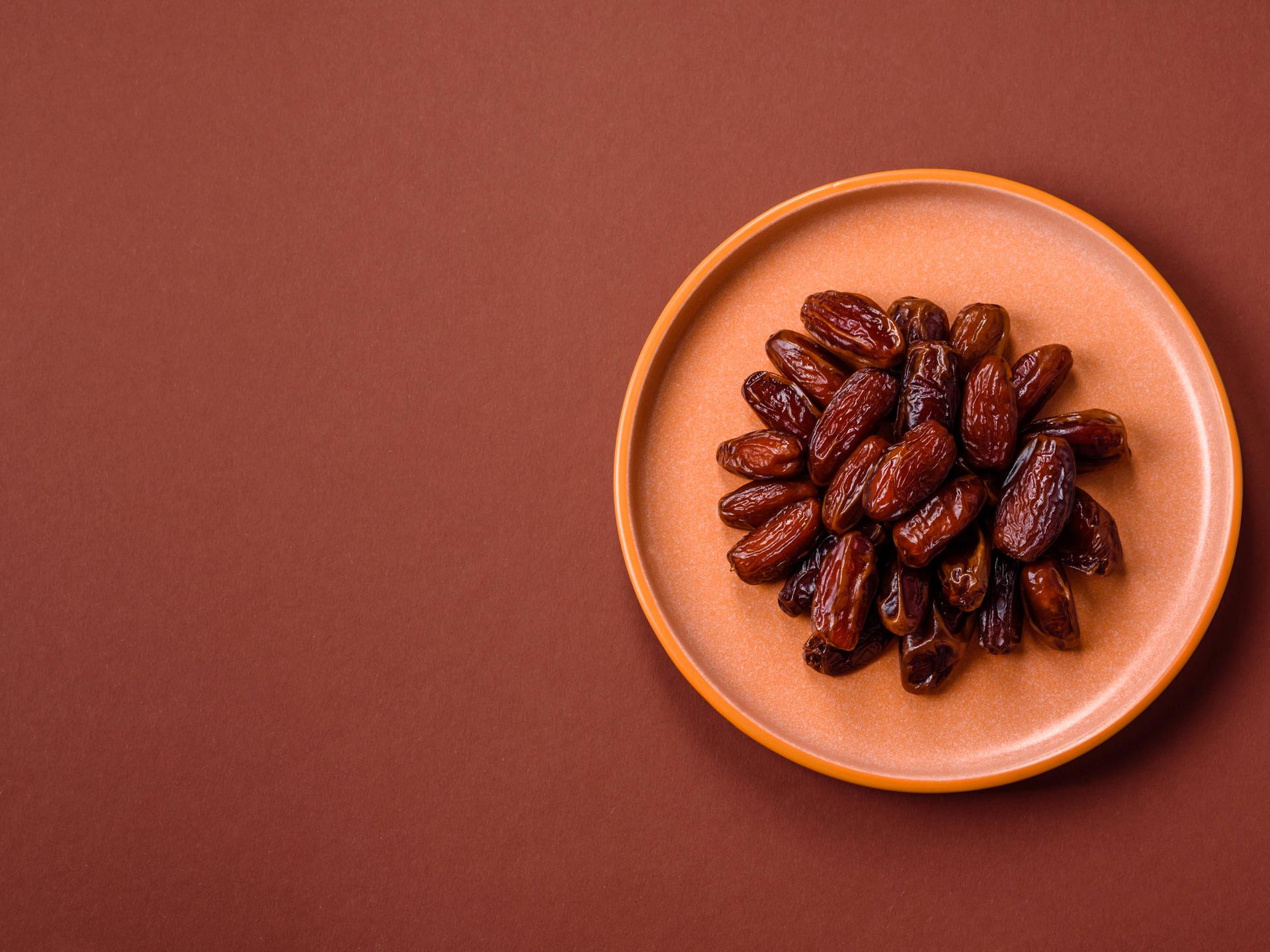 Getrocknete Datteln in einem Keramikteller, arabisches Essen für den Ramadantisch. 