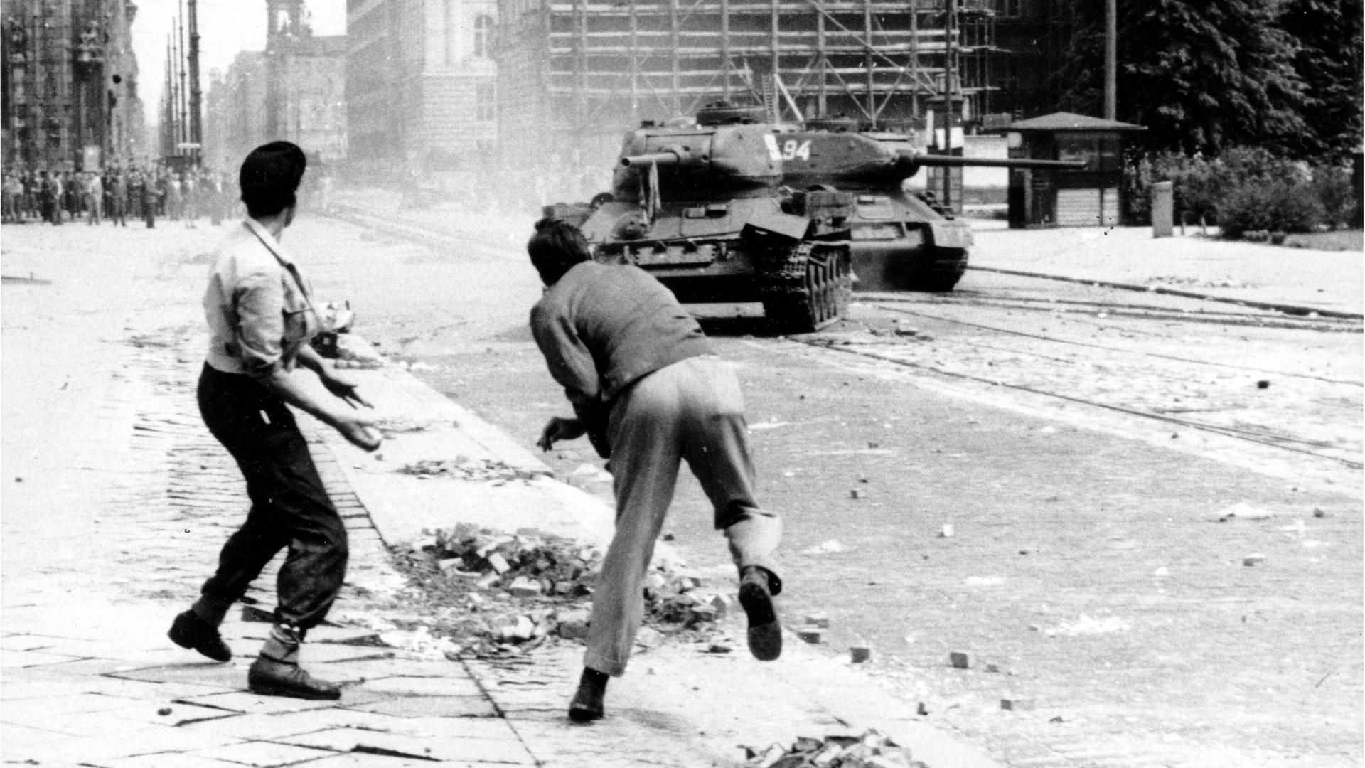Zwei Demonstranten in Ost-Berlin werfen Steine nach sowjetischen Panzern am Leipziger PLatz 1953. 
