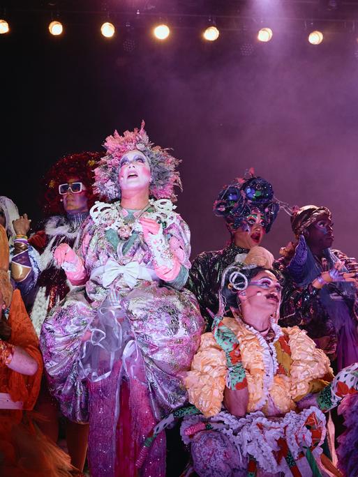 Verkleidete Menschen stehen auf der Bühne der Performance "Bark of Millions".