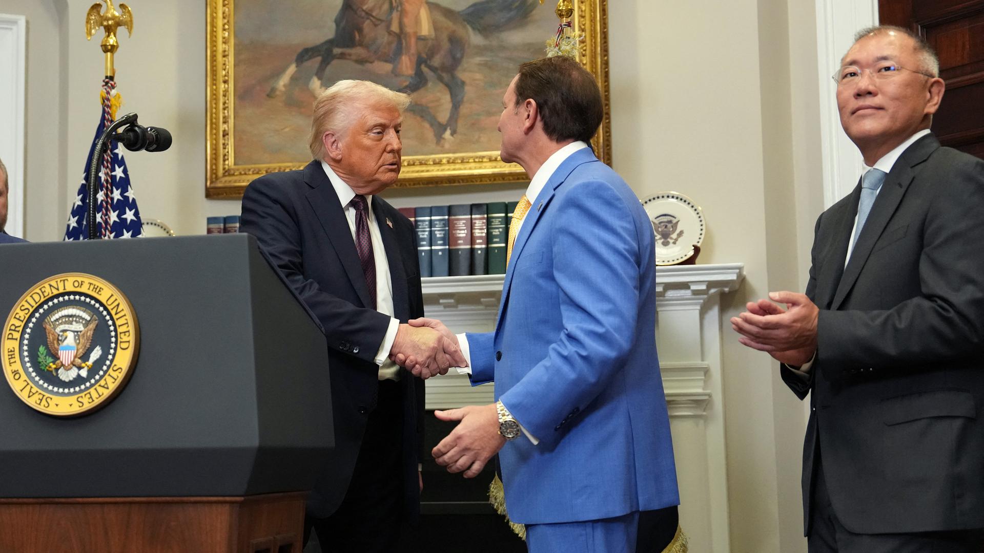 US-Präsident Trump schüttelt dem Gouverneur von Louisiana, Landry, die Hand. Rechts daneben steht Hyundai-Chef Chung. 