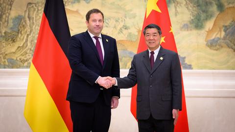 Lars Klingbeil (l, SPD), Bundesminister der Finanzen, und He Lifeng, Vize-Premierminister von China für Wirtschaft und Finanzen, schütteln sich die Hand. Hinter ihnen sind die Flaggen Deutschlands und Chinas. 