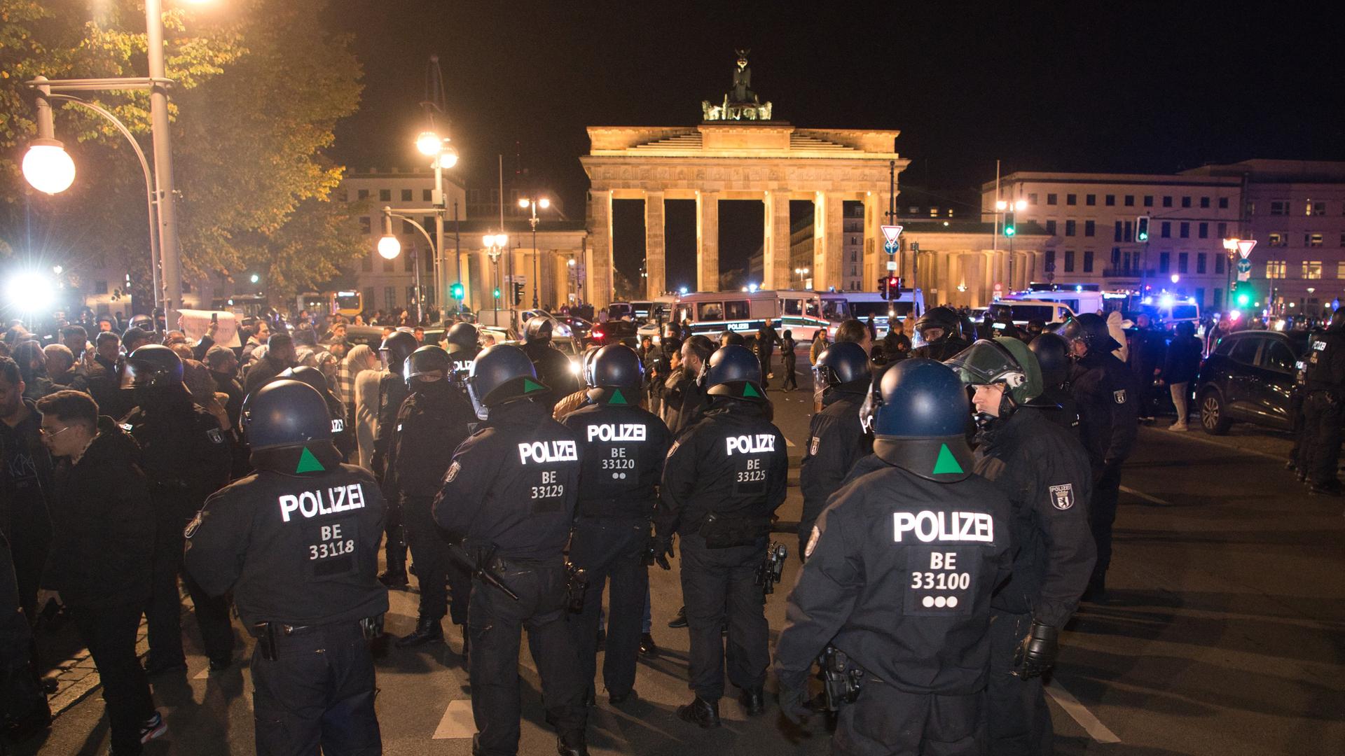 Vor dem Brandenburger Tor in Berlin gibt es eine Pro-Palästina Kundgebung. Auf dem Foto sieht man die Einsatzkräfte der Polizei. Das Brandenburger Tor ist hell erleuchtet.