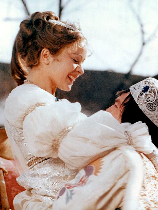 Filmszene aus "Drei Haselnüsse für Aschenbrödel": Der festlich gekleidete Prinz hält die Prinzessin in weißem Prachtkleid hoch.