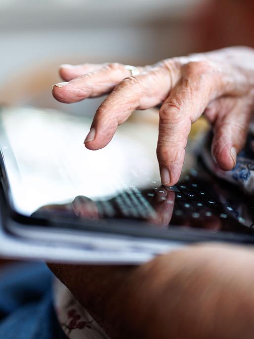 Eine 95-jährige Dame bedient ihr Tablet und schreibt eine Nachricht in einem Messenger.