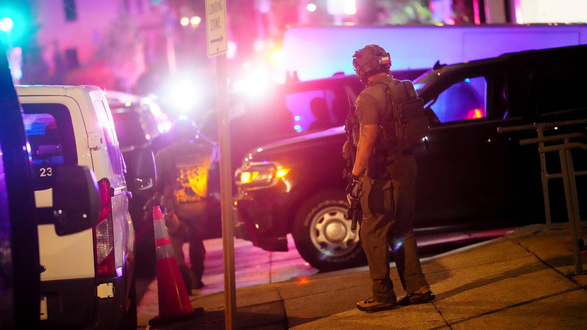 Einsatzkräfte mit militärischer Ausrüstung stehen nachts auf einer grell ausgeleuchteten Straße und sichern die Gegend