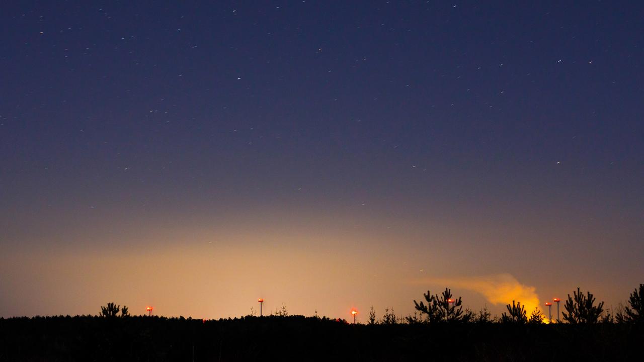 Symbolfoto Lichtverschmutzung, ein Lichtschein der Stadt Cottbus ist ueber der Landschaft am Nachthimmel zu sehen.