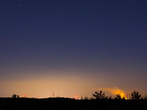 Symbolfoto Lichtverschmutzung, ein Lichtschein der Stadt Cottbus ist ueber der Landschaft am Nachthimmel zu sehen.