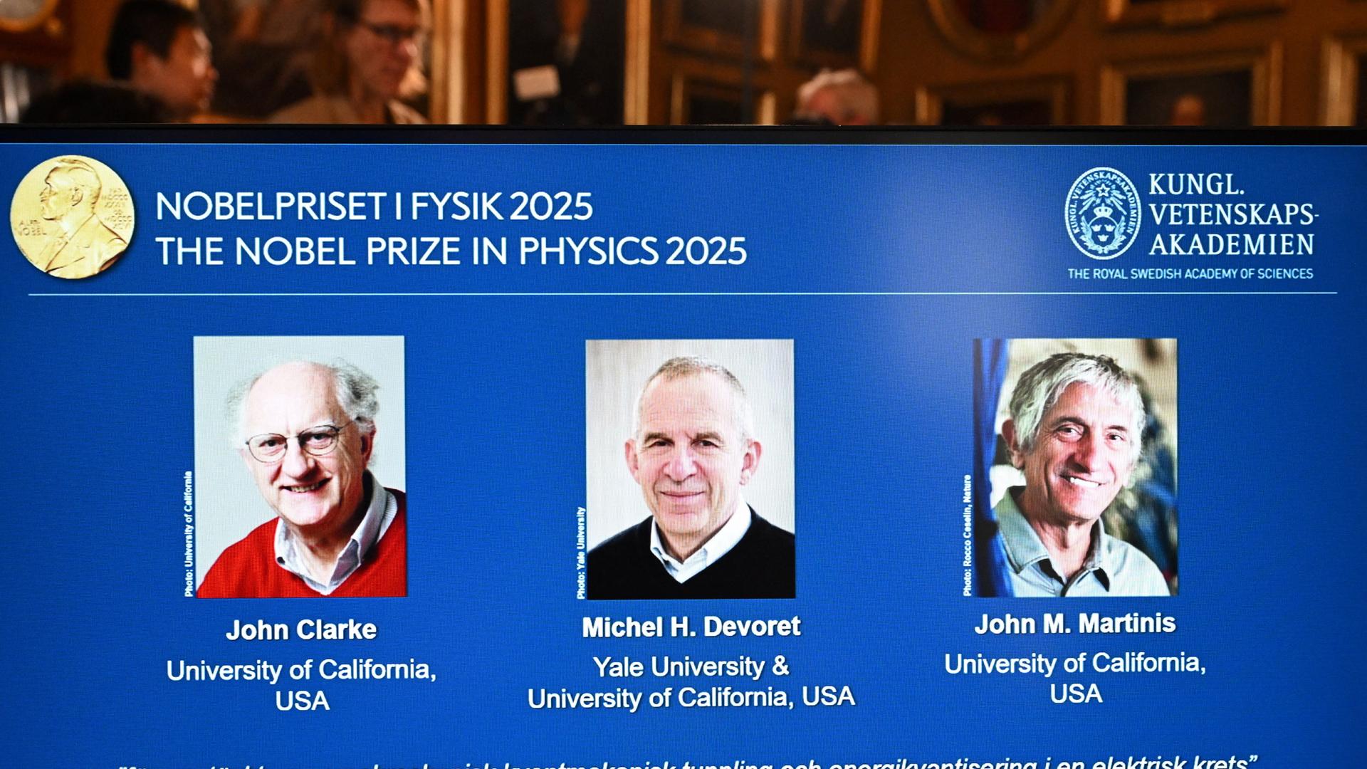 Standbild aus dem Livestream zur Bekanntgabe der Gewinner: Auf einer Leinwand sind - von links nach rechts - John Clarke, Michel Devoret und John Martinis zu sehen.