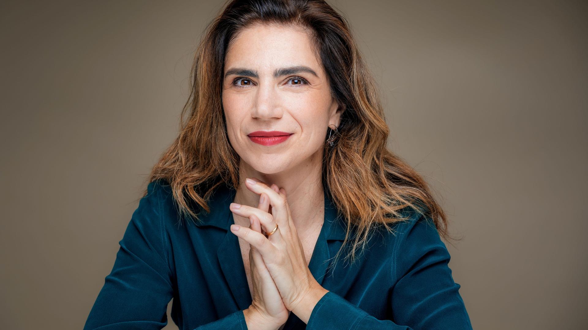 Dana Grigorcea lächelt in die Kamera. Sie hat braunes, schulterlanges Haar und trägt eine petrolblaue Bluse. Dana Grigorcea lächelt in die Kamera. Sie hat braunes, schulterlanges Haar und trägt eine petrolblaue Bluse.