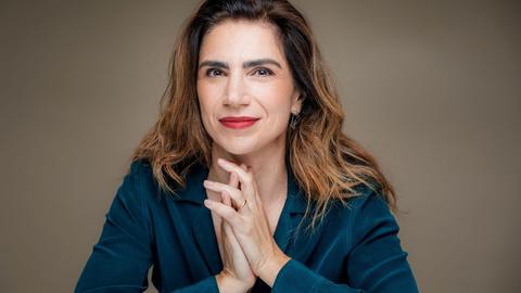 Dana Grigorcea lächelt in die Kamera. Sie hat braunes, schulterlanges Haar und trägt eine petrolblaue Bluse.