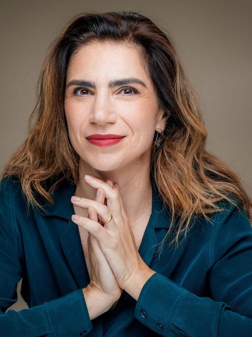 Dana Grigorcea lächelt in die Kamera. Sie hat braunes, schulterlanges Haar und trägt eine petrolblaue Bluse.