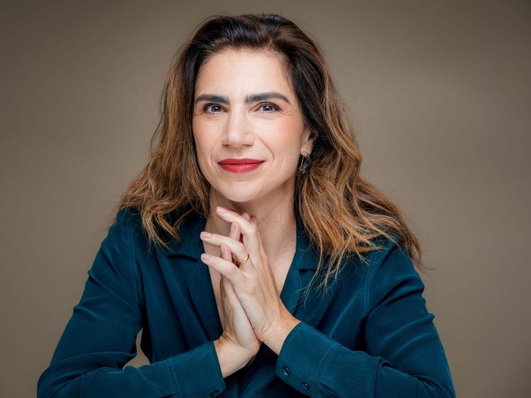 Dana Grigorcea lächelt in die Kamera. Sie hat braunes, schulterlanges Haar und trägt eine petrolblaue Bluse.