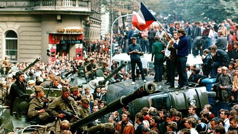 August 1968, Tschechoslowakei, Prag: Protestierer umringen in der Innenstadt sowjetische Panzer und stehen mit einer Fahne der Tschechoslowakei auf einem umgekippten Militärfahrzeug.