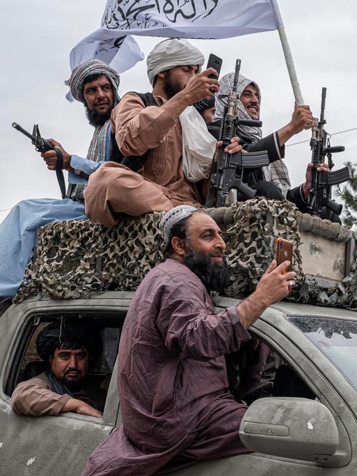 Talibankämpfer fahren Waffen und Fahnen schwenkend am Jahrestag der Machtübernahme durch Kabul,  15. August 2022. -