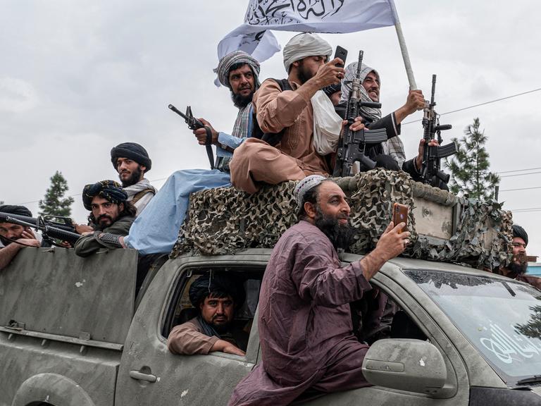 Talibankämpfer fahren Waffen und Fahnen schwenkend am Jahrestag der Machtübernahme durch Kabul,  15. August 2022. -