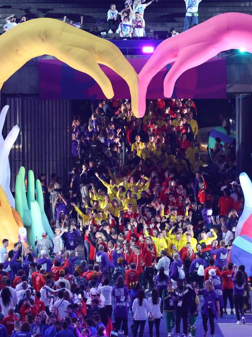 Die Eröffnungs-Feier von den Special Olympics in Berlin. Die Sportlerinnen und Sportler laufen durch zwei aufblasbare bunte Hände. Sie formen ein Herz.