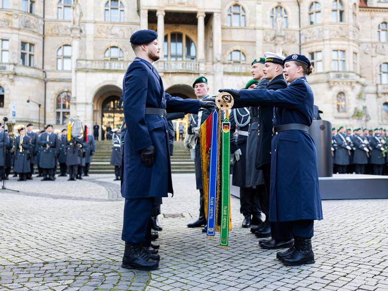 Rekruten stehen beim feierlichen Gelöbnis zum 69. Gründungstag der Bundeswehr für den Eid um eine Deutschlandflagge. Rund 230 Rekruten legten am 12..11.2024 ihr Gelöbnis auf dem Platz der Menschenrechte vor dem Neuen Rathaus in Hannover ab.