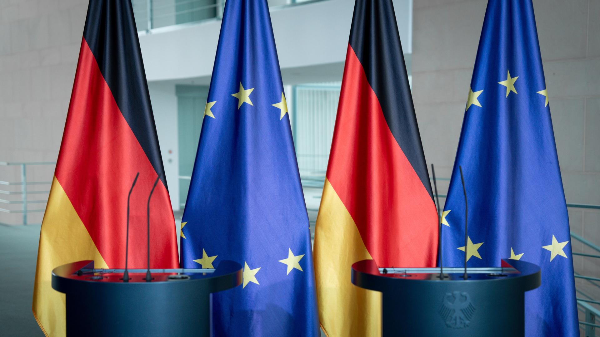 Flaggen von der EU und Deutschland vor dem Rednerpult im Bundeskanzleramt in Berlin