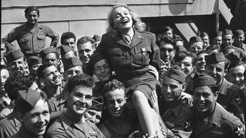 Von Soldaten der US-Armee hochgehalten: die in Deutschland geborene amerikanische Schauspielerin und Musikerin Marlene Dietrich, New York 1945. Von Soldaten der US-Armee hochgehalten: die in Deutschland geborene amerikanische Schauspielerin und Musikerin Marlene Dietrich, New York 1945.
