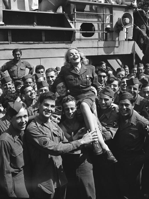 Von Soldaten der US-Armee hochgehalten: die in Deutschland geborene amerikanische Schauspielerin und Musikerin Marlene Dietrich, New York 1945.