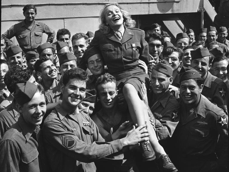 Von Soldaten der US-Armee hochgehalten: die in Deutschland geborene amerikanische Schauspielerin und Musikerin Marlene Dietrich, New York 1945.