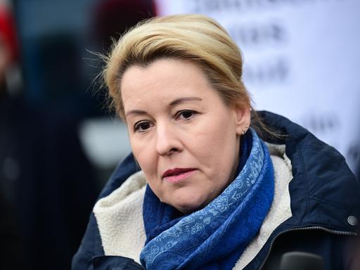 Die Berliner Wirtschaftssenatorin Franziska Giffey (SPD) steht mit dunklem Mantel und blauem Schal in einer Notunterkunft