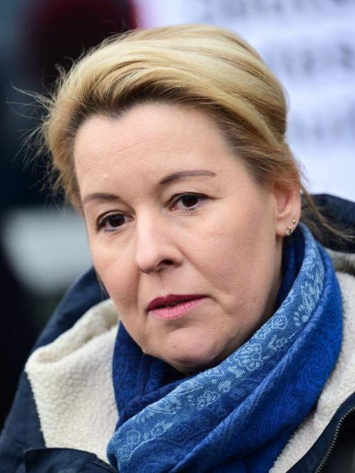 Die Berliner Wirtschaftssenatorin Franziska Giffey (SPD) steht mit dunklem Mantel und blauem Schal in einer Notunterkunft