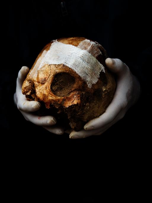 Ein Freiwilliger hält einen Schädel in der Hand, bevor er ihn bei der Exhumierung eines Massengrabs in Spanien in eine Kiste legt.