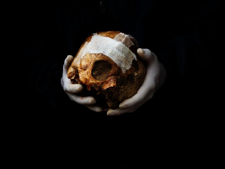 Ein Freiwilliger hält einen Schädel in der Hand, bevor er ihn bei der Exhumierung eines Massengrabs in Spanien in eine Kiste legt.