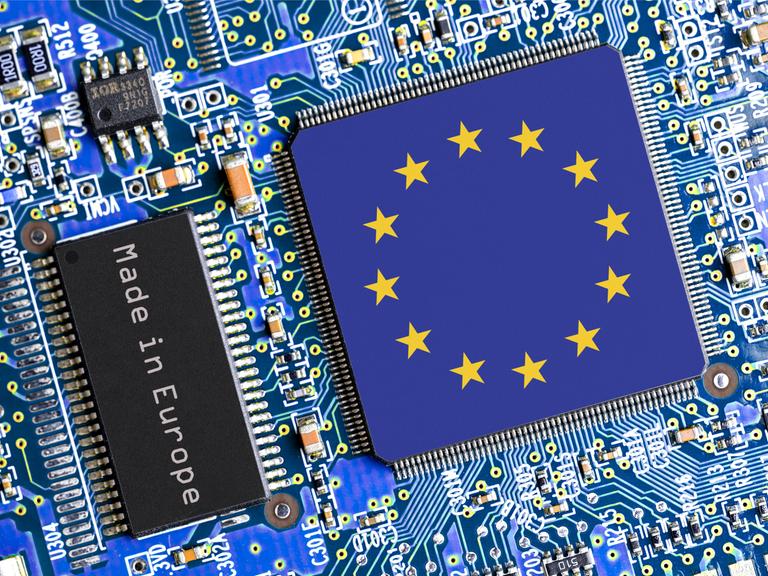 Eine blaue Platine mit diversen Halbleitern und zwei Chips. Einer trägt die Aufschrift "Made in Europe", der andere, größere, zeigt die Flagge der EU