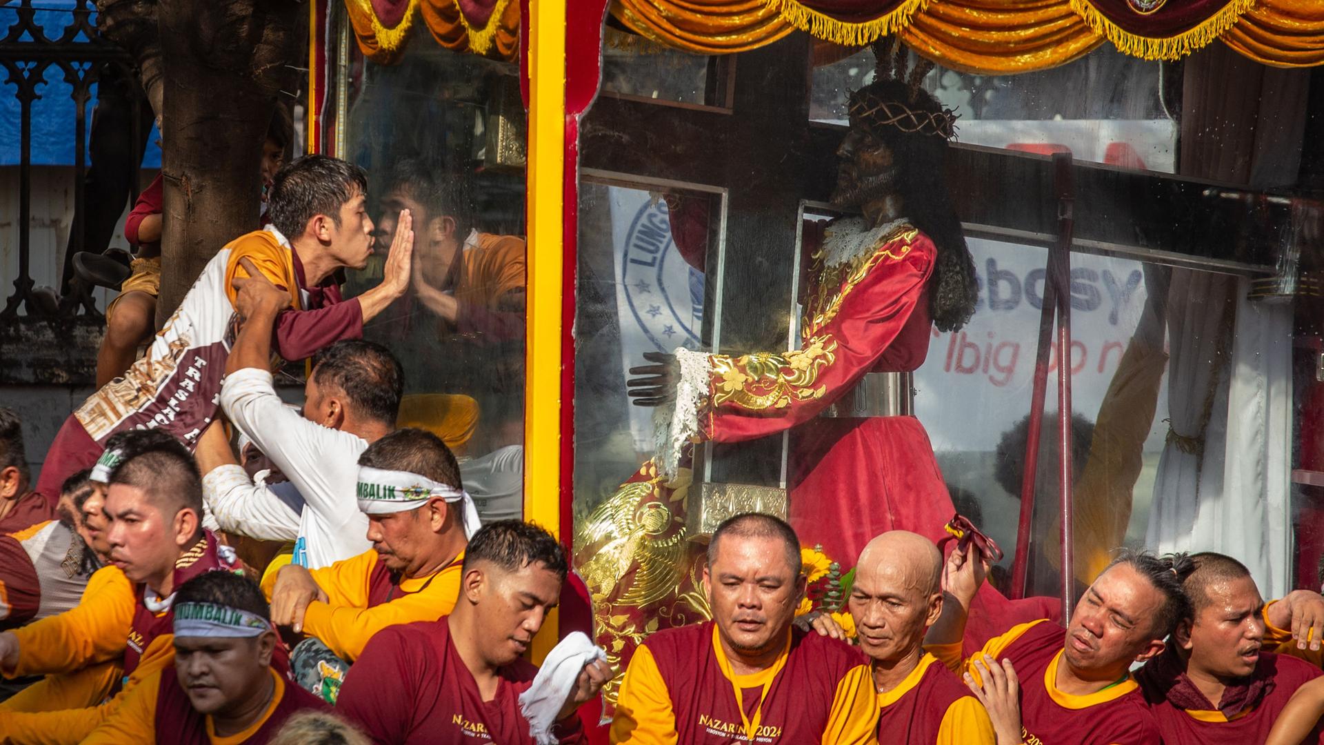 Ein Gläubiger küsst die Vitrine mit der "Schwarzer Nazarener" geküssten Holzstatue. Darunter Gedränge. Ein Gläubiger küsst die Vitrine mit der "Schwarzer Nazarener" geküssten Holzstatue. Darunter Gedränge.