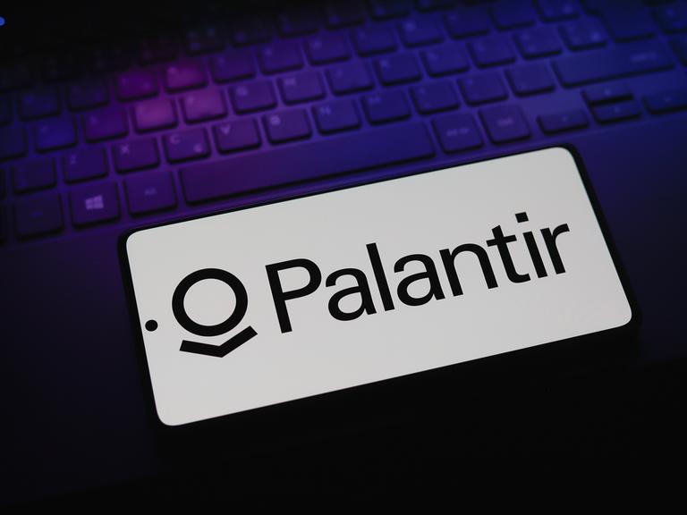 Das Logo der Firma Palantir Technologies erscheint auf einem Smartphone, das auf einer Computertastatur liegt.
