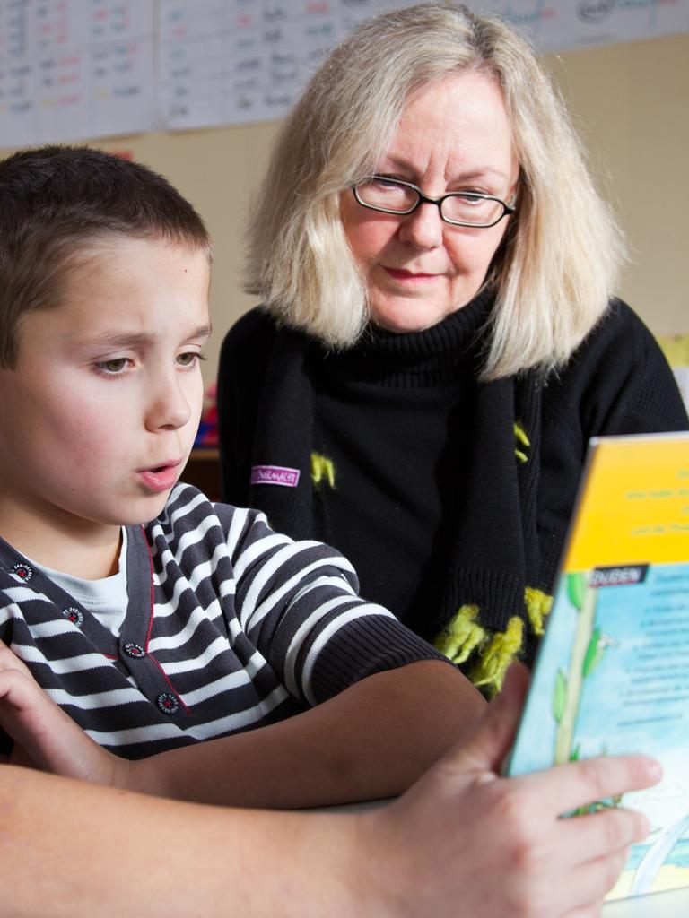 Ein Junge und seine Lesepatin lesen gemeinsam ein Buch an einer Grundschule in Münster.