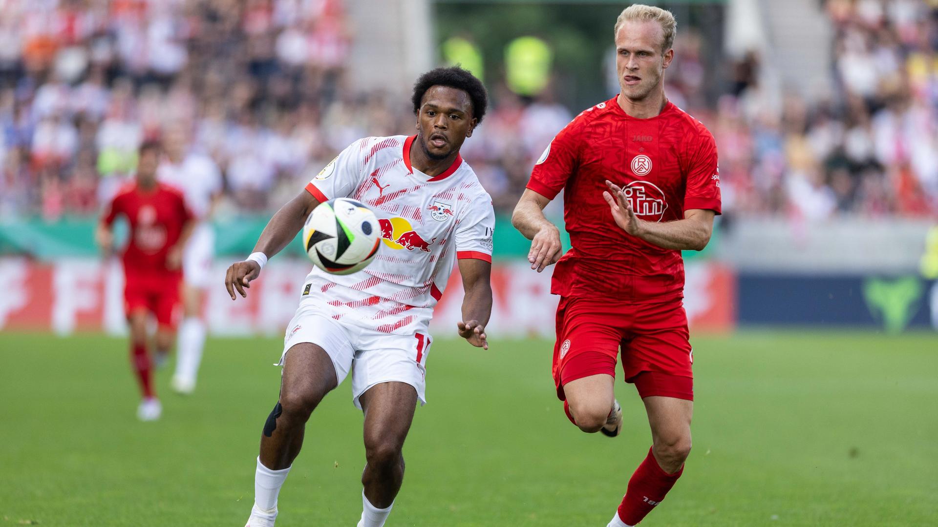 Ein Leipziger Fußballspieler und ein Essener Fußballspieler rennen dem Ball hinterher. Ein Leipziger Fußballspieler und ein Essener Fußballspieler rennen dem Ball hinterher.