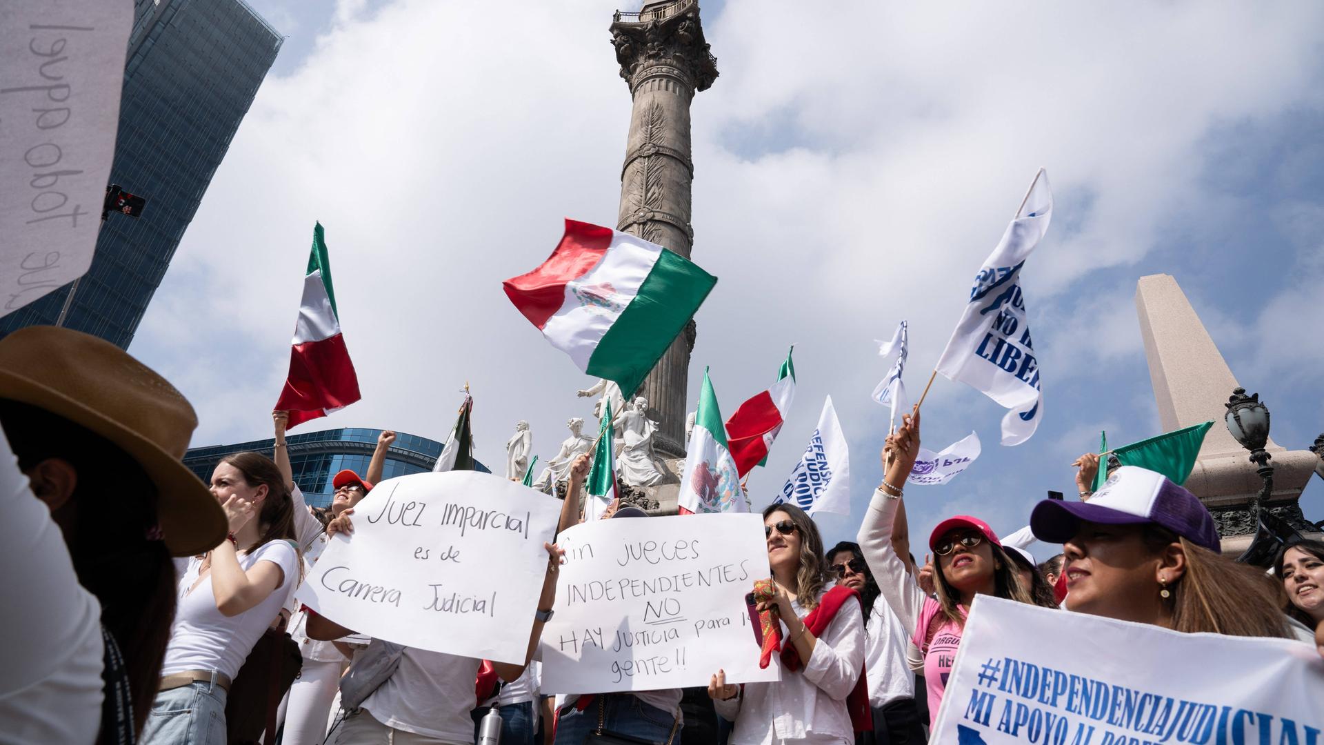 Demonstranten in Mexiko schwenken Fahnen und halten Plakate hoch.