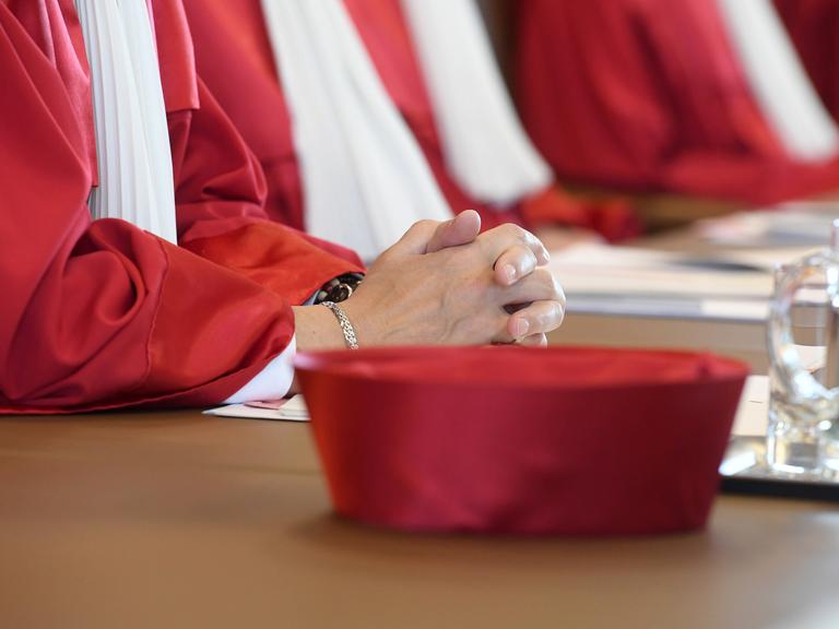 Die Nahaufnahme zeigt die gefalteten Hände einer Richterin und den Hut, der zur Robe des Bundesverfassungsgerichts gehört.