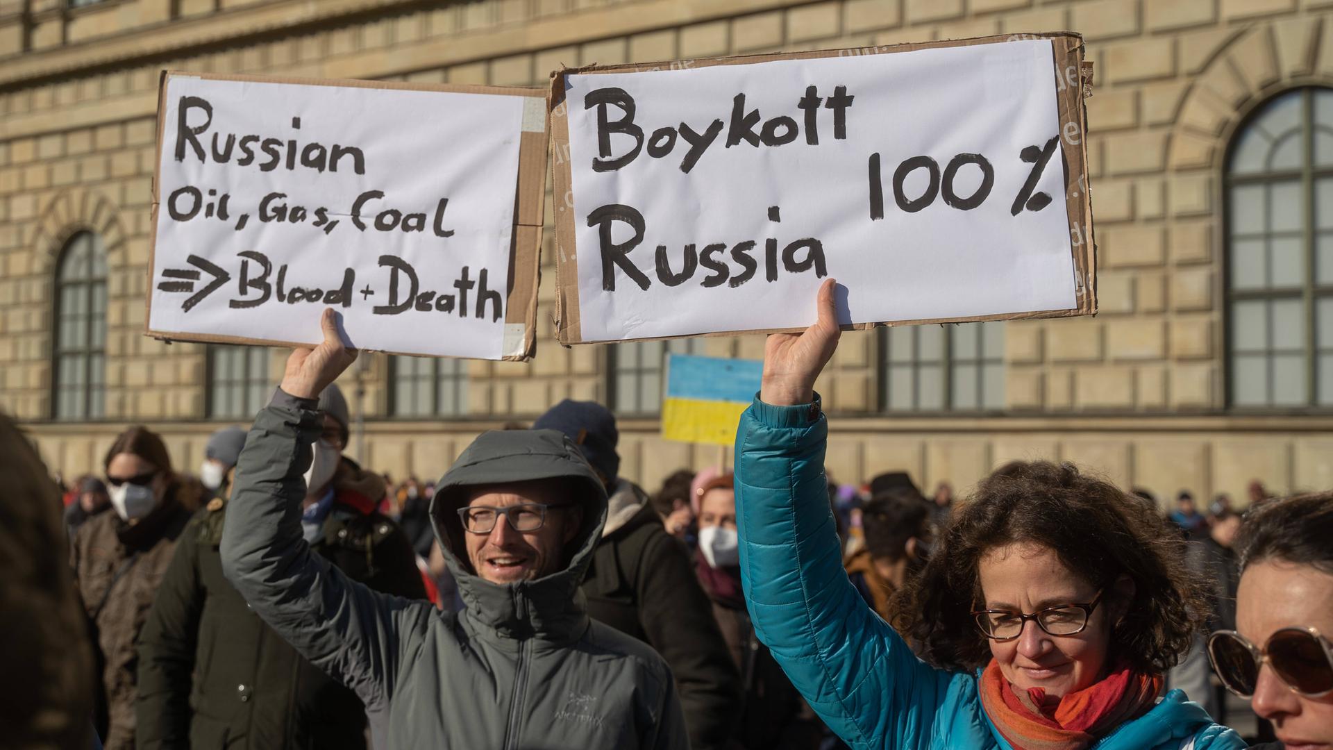 Demonstranten rufen bei einer Demonstration in München zu einem Boykott gegen Russland auf. 