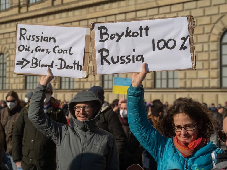 Demonstranten rufen bei einer Demonstration in München zu einem Boykott gegen Russland auf. 