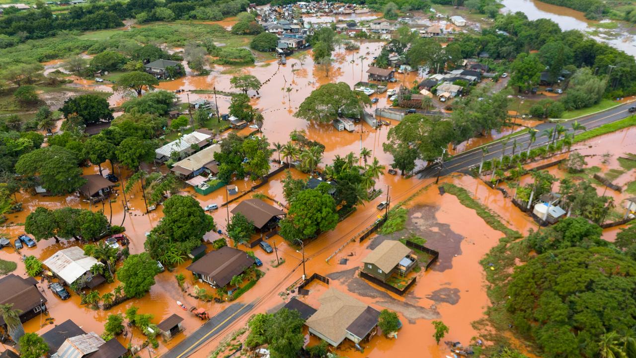 Eine Luftaufnahme zeigt eine überschwemmte Ortschaft auf der Insel Hawaii. Straßen und Autos werden von schlammigem Wasser überflutet. 