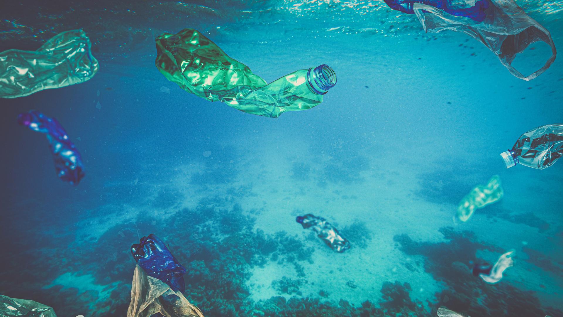 Plastikmüll wie Flaschen und Tüten schwimmen im türkisfarbenen Meer. Plastikmüll wie Flaschen und Tüten schwimmen im türkisfarbenen Meer.