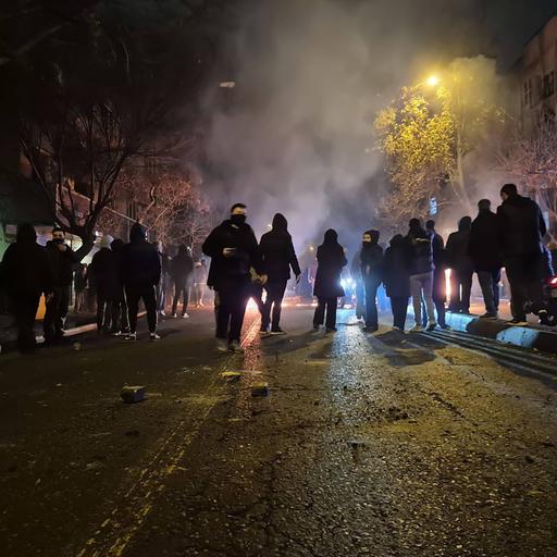 Auf diesem Bild vom 9.1. aus Teheran sind zahlreiche Protestierende zu erkennen. Es ist Nacht, auf der Straße spiegelt sich das Licht. Die Personen sind vermummt. 