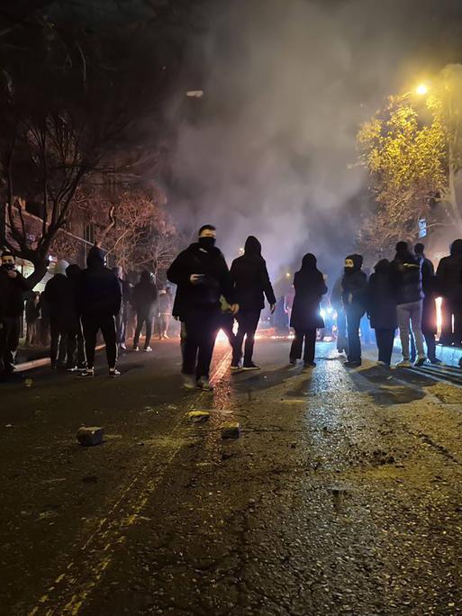 Auf diesem Bild vom 9.1. aus Teheran sind zahlreiche Protestierende zu erkennen. Es ist Nacht, auf der Straße spiegelt sich das Licht. Die Personen sind vermummt. Auf diesem Bild vom 9.1. aus Teheran sind zahlreiche Protestierende zu erkennen. Es ist Nacht, auf der Straße spiegelt sich das Licht. Die Personen sind vermummt.