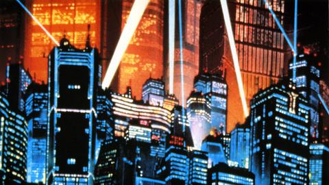 Eine Aufnahme aus dem Anime-Film Akria aus dem Jahr 1988. Es ist die von Scheinwerfern angeleuchtete Skyline der Stadt Neo-Tokyo mit vielen Hochäusern.