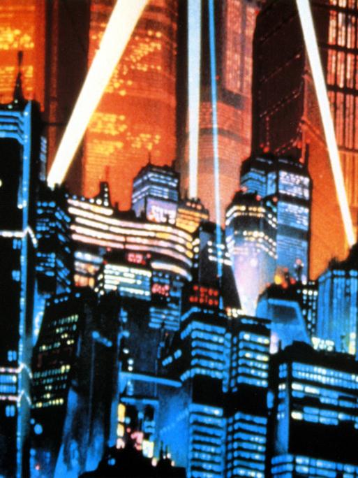 Eine Aufnahme aus dem Anime-Film Akria aus dem Jahr 1988. Es ist die von Scheinwerfern angeleuchtete Skyline der Stadt Neo-Tokyo mit vielen Hochäusern.