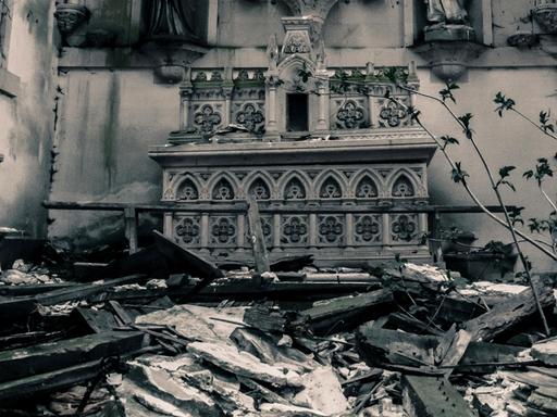 Blick in einen Krichenraum mit Altar, in den das Dach eingestürzt ist und damit den Raum unpassierbar macht.