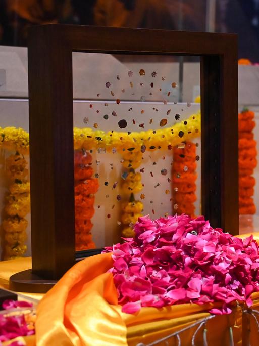 Eine Glasscheibe mit Edelsteinen steht auf einem mit Blumen geschmückten Tisch 