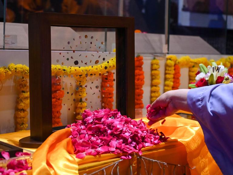 Eine Glasscheibe mit Edelsteinen steht auf einem mit Blumen geschmückten Tisch 